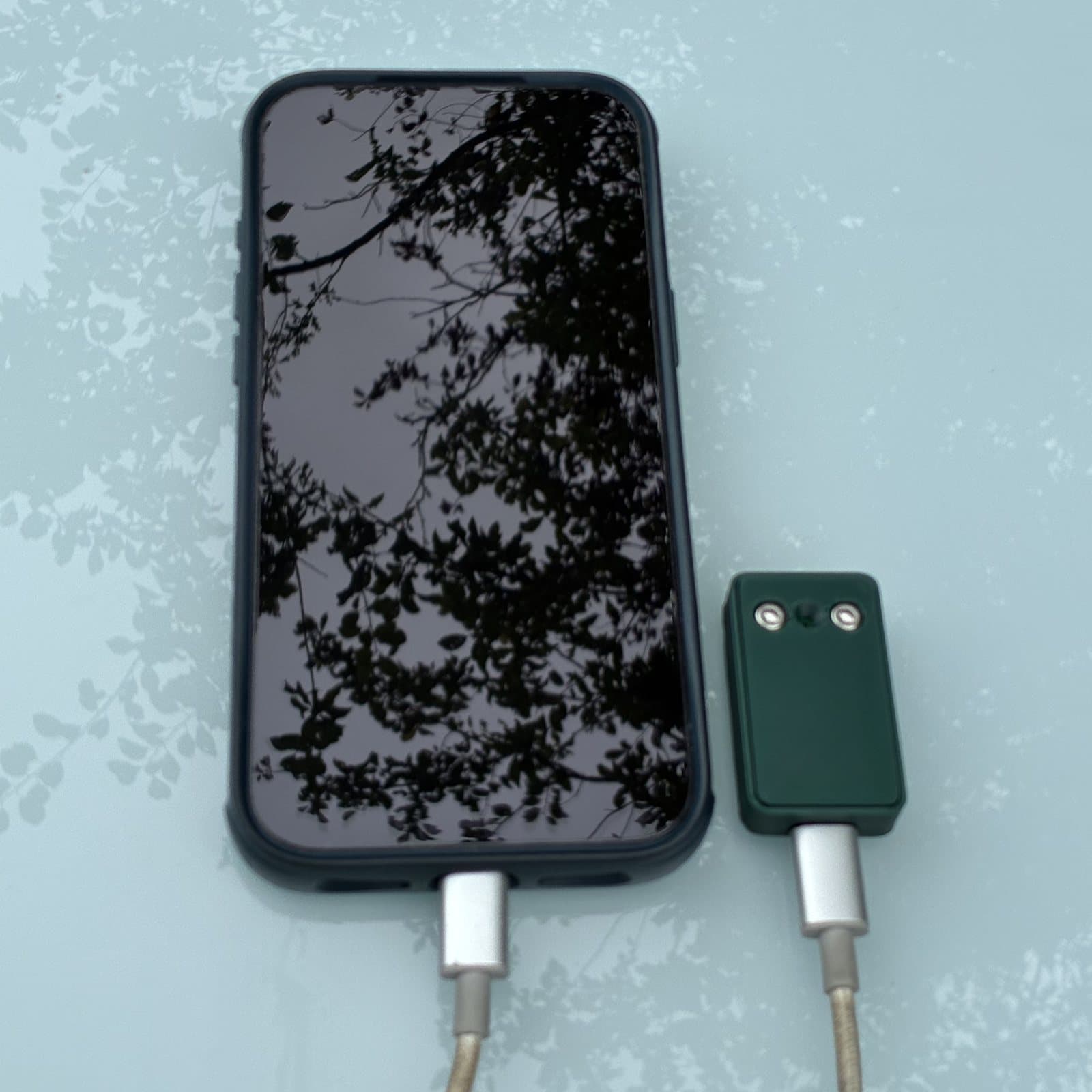 The bat dongle connected to a phone by a short USB-C cable, both lying on a table.